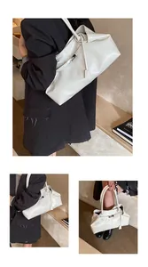 Detail of white glossy leather tote bag showing unique fold design and thin strap accents