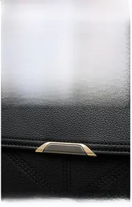 Close-up of textured black leather handbag with dual-tone metal magnetic buckle and V-quilting