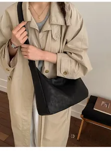 Close-up of black leather hobo bag texture on a model wearing a khaki trench coat