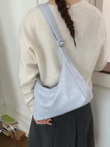 Minimalist light blue dumpling bag shown on shoulder in a clean indoor setting
