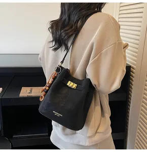 Detail einer schwarzen Beuteltasche mit goldenem Drehverschluss und Perlenanhänger