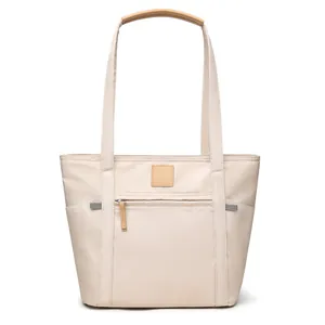 Minimalist beige nylon tote bag with brown handles and front zipper pocket for daily commute