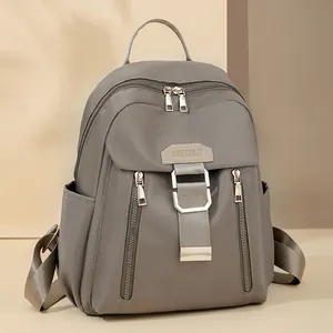 Waterproof grey nylon travel backpack with gold hardware and multiple zipper pockets