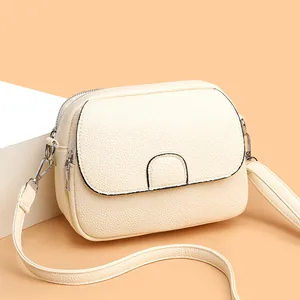 Chic cream mini crossbody bag with lychee texture and silver hardware in a studio setting