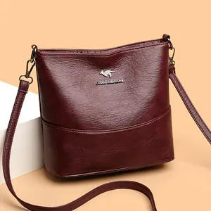Minimalist burgundy leather bucket bag with silver kangaroo emblem on a modern display block