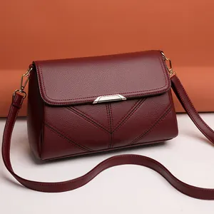 Elegant burgundy leather crossbody bag with V-shaped stitching and golden metal clasp