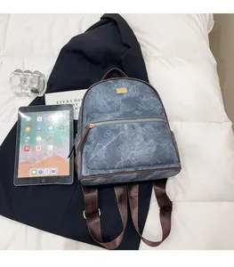 Macro shot of blue denim clover patterned backpack with brown leather trim and gold hardware