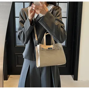Détail du sac trapèze en cuir kaki avec fermoir pivotant en métal et poignée élégante