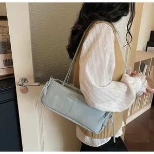 Detail of light blue faux leather baguette bag with side drawstring and metal fashion tag