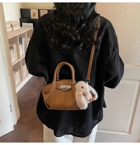 Detail of brown litchi pattern leather bucket bag with silver lock and rabbit charm
