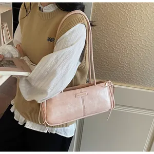 Detail of light pink shoulder bag with decorative side bows and metal fashion plaque