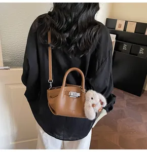Detail of brown lychee grain leather bucket bag featuring a plush rabbit pendant decoration