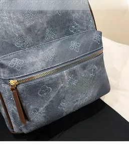 Detailed shot of washed denim backpack with floral embroidery and golden metal zipper