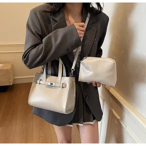 Détail d'un ensemble de sacs brillants blanc cassé avec ferrures argentées sur modèle