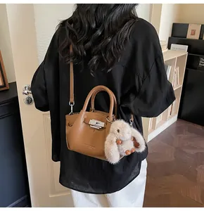 Detail of a brown lychee pattern leather bucket bag with silver clasp and plush bunny charm