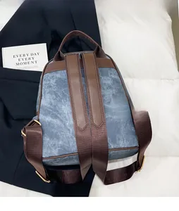 Close-up of adjustable brown straps and golden metal buckles on blue denim backpack