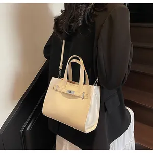 Détail d'un sac bandoulière beige avec fermoir rotatif métallique et doubles poignées