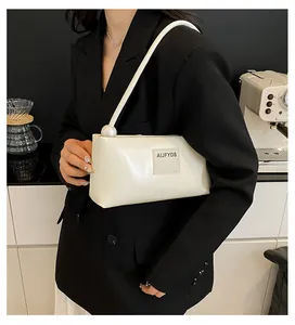 Détail du sac sous le bras en cuir blanc cassé avec une grande perle sur la bandoulière