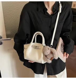 Detail of white lychee leather bucket bag with silver lock and plush rabbit charm