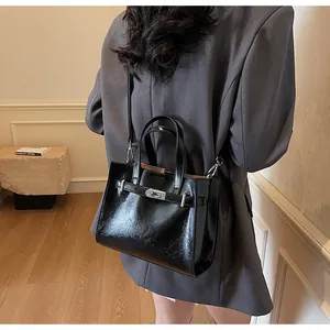Vue détaillée d'un sac carré en cuir noir brillant avec un fermoir rotatif argenté