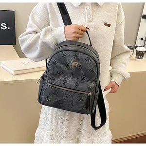 Close-up of dark grey embossed floral backpack with metallic logo plate on model