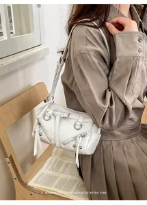 Detail view of white punk style shoulder bag with multiple metal zippers and buckles