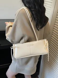 Cream white rectangular leather baguette bag with bow details and shoulder strap