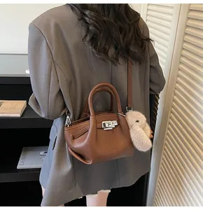 Detail of dark brown litchi pattern leather bucket bag with cute plush rabbit charm