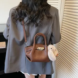 Brown litchi leather bucket bag with metal lock, top handle and plush rabbit charm