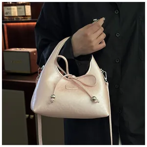 Dettaglio della borsa rosa in PU con fiocco decorativo e accenti di perline metalliche