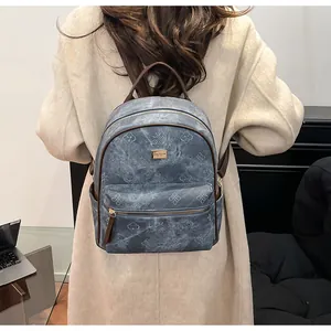 Detail of blue textured backpack with embossed floral patterns and golden logo plate