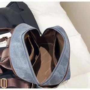 Interior view of denim tote backpack with brown lining, zip pocket and golden buckles