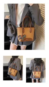 Detalle de bolso cubo caqui con colgante de caballo y correa ajustable de mujer