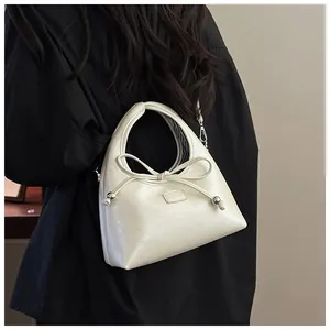 Dettaglio della borsa a mano bianco crema con elegante fiocco e dettagli in perle argento