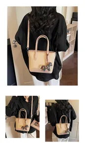 Detalle del bolso de lona beige con ribete de cuero rosa y colgante decorativo de caballo