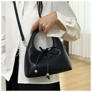 Dettaglio della borsa hobo in pelle lucida nera con fiocco e perle di metallo