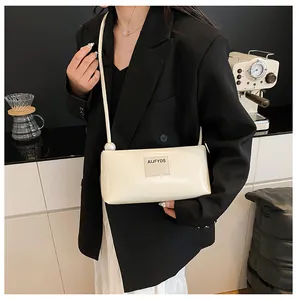 Détail du sac baguette blanc avec perle sur la bandoulière fine en similicuir