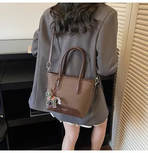Detalle de bolso cubo de fieltro con asas de cuero y un colgante en forma de caballo