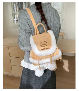 Close-up of suede mini backpack with plush trim, cat embroidery and fluffy pompoms