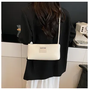 Gros plan d'un sac baguette blanc crème avec écusson logo minimaliste sur le devant