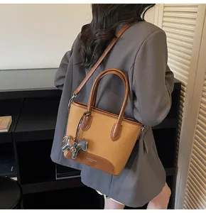 Detalle del bolso cubo de lana camel y cuero marrón con un pequeño colgante de caballo
