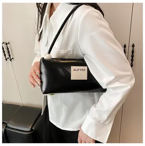 Détail du sac sous le bras noir en similicuir avec perle géante et écusson de logo