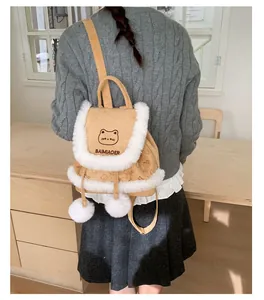Detail of cute brown plush mini backpack with white fluffy poms and cat embroidery