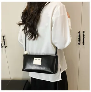 Détail du sac baguette noir avec patch logo blanc et perle décorative blanche