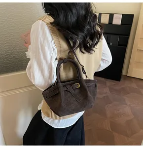 Détail du sac seau en daim marron avec design plissé et boucle dorée élégante