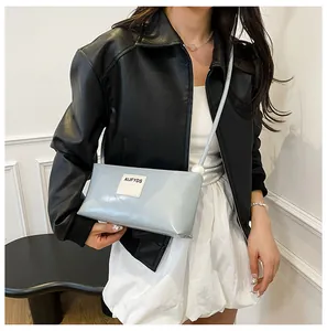 Détail du sac baguette bleu clair avec perle blanche et écusson logo minimaliste