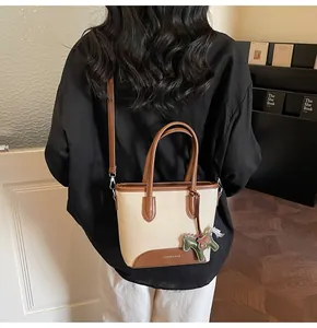 Detalle del bolso tipo cubo de lona con adornos de cuero y colgante de caballo