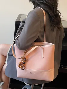 Sac cabas rose avec pampille en bois porté à l'épaule sur un blazer gris élégant