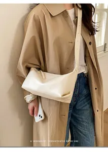 Detailed view of minimalist off-white leather shoulder bag with sleek wide strap