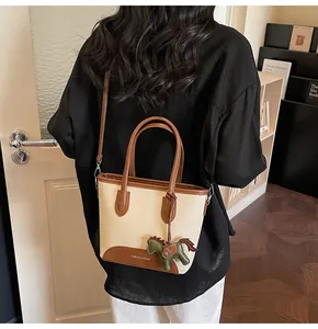 Detalle de bolso tipo cubo de lona con adornos de cuero y colgante de poni decorativo